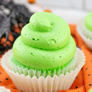 halloween slime cupcakes with green frosting on it. on an orange linen