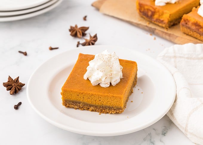 Pumpkin cheesecake bars served on a white plate.