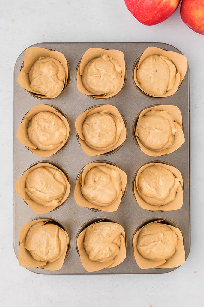 A muffin tin filled with apple cider cupcake batter