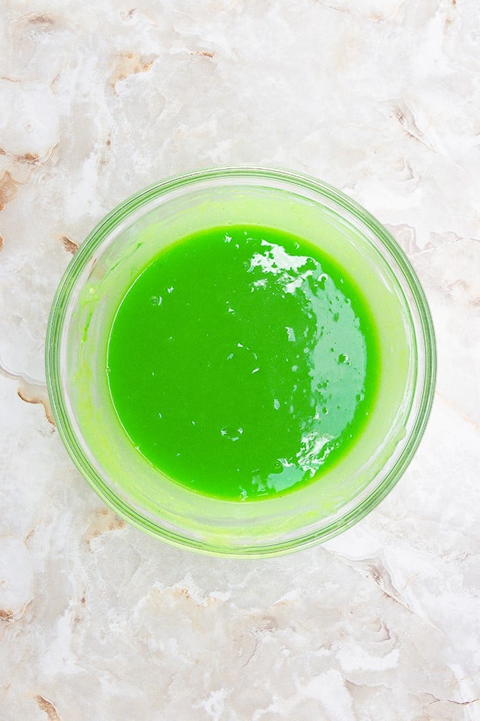 Lime green slime in a glass bowl on a marble surface.