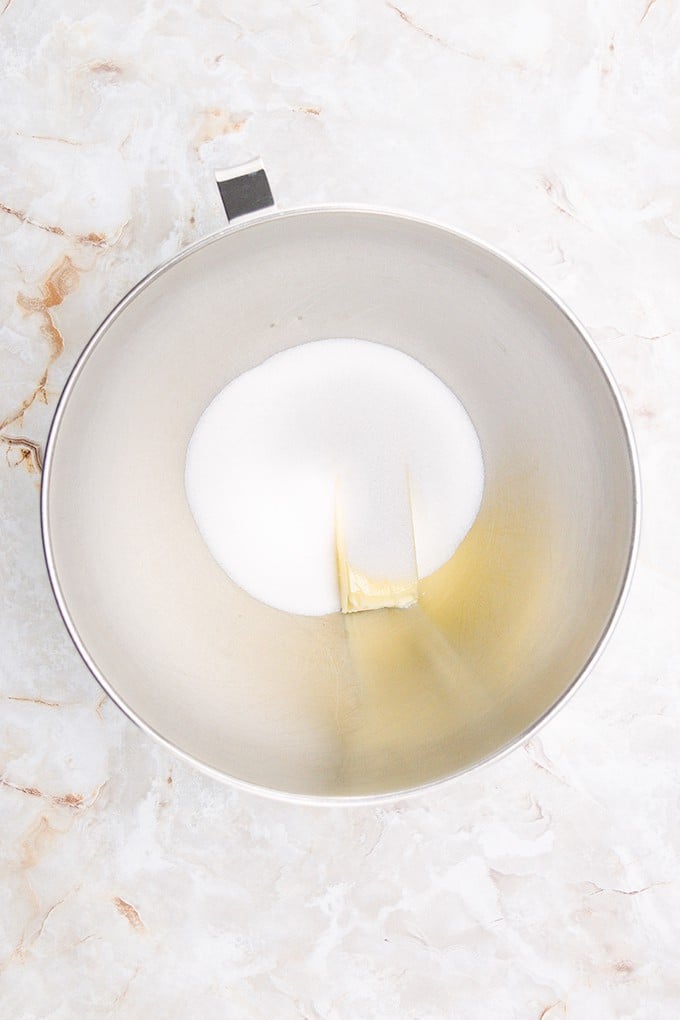 A lime-colored bowl with a spoon in it on a marble surface.