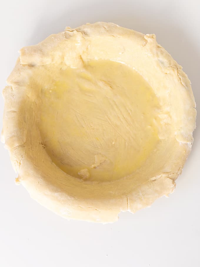homemade pie crust in a pie plate on a white surface