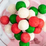 A glass bowl filled with red, green, and white Christmas truffles.