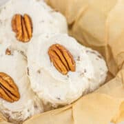 Divinity Candy coated pecan cookies in a basket with icing and pecans.