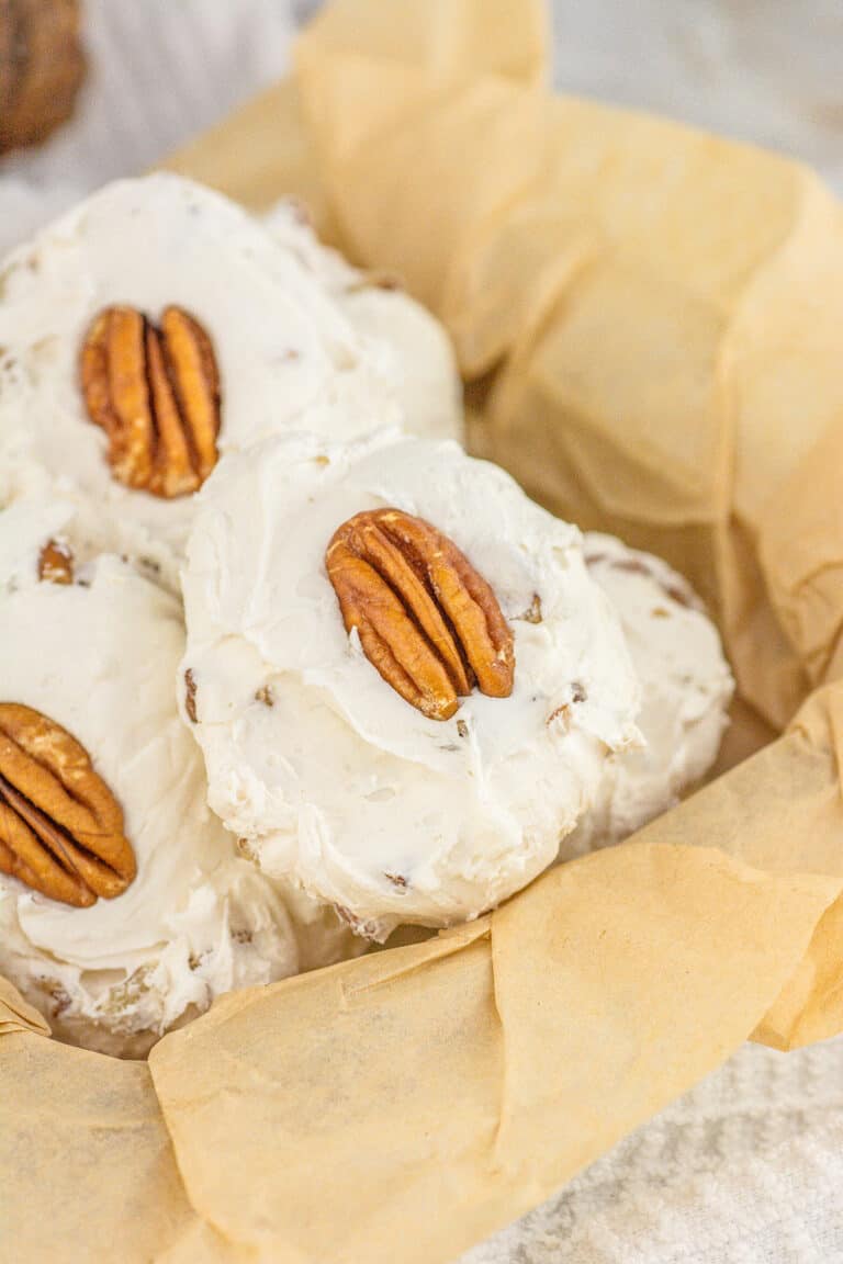 Divinity Candy coated pecan cookies in a basket with icing and pecans.