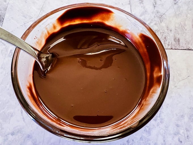 Martha Washington Candy with melted chocolate in a glass bowl and spoon.