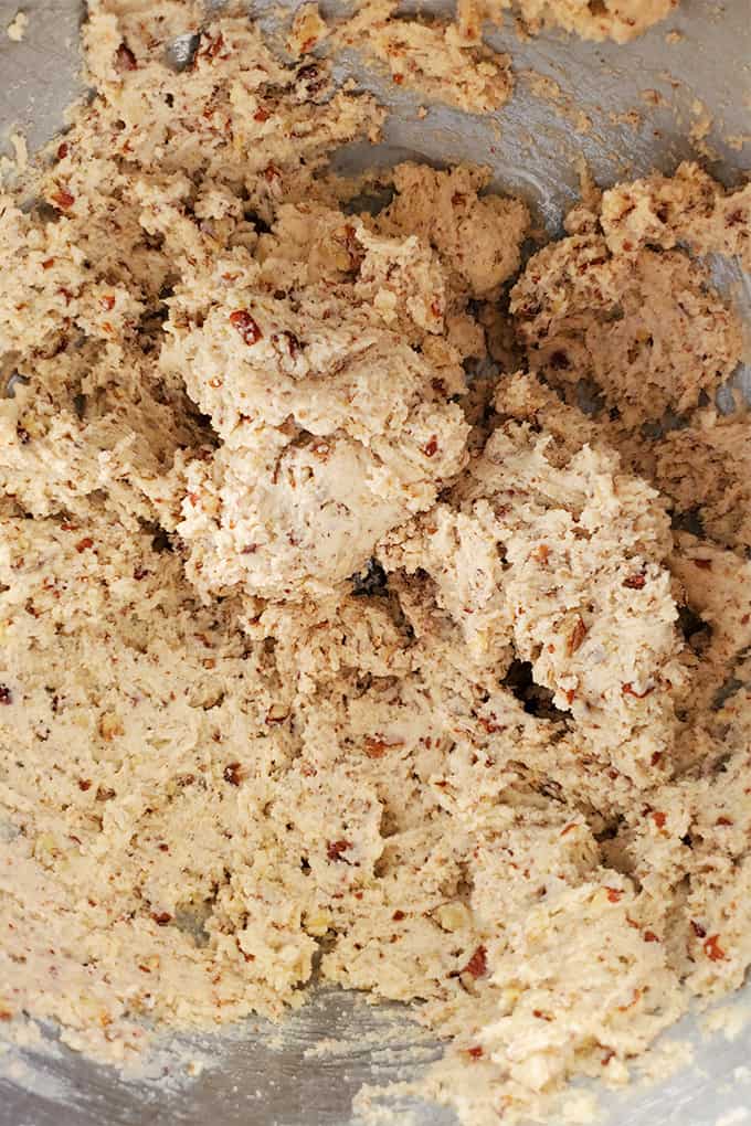 A metal mixing bowl with pecan snowball cookies dough in it.