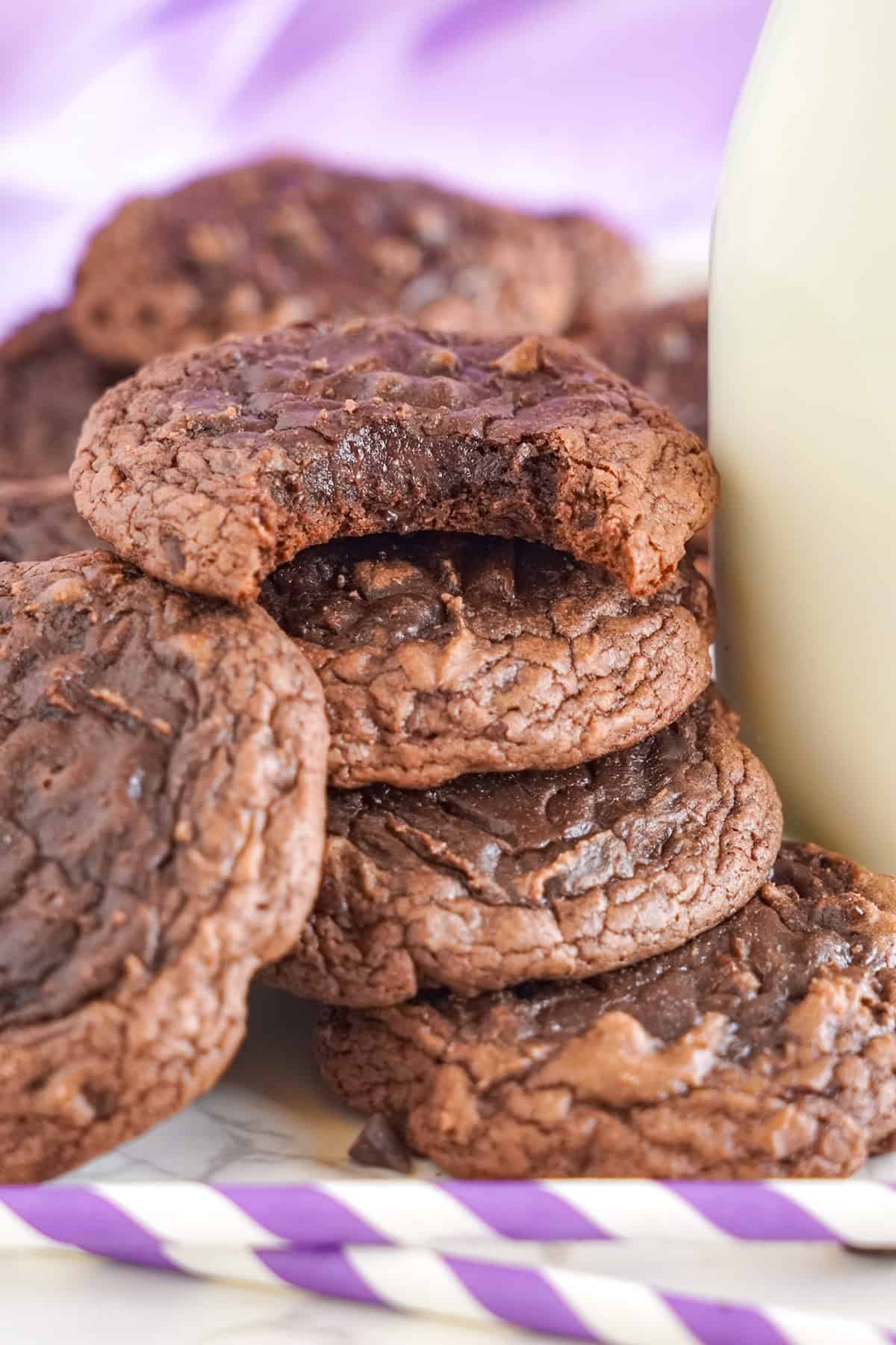 A plate of brownie mix cookies with a bite taken out of them.