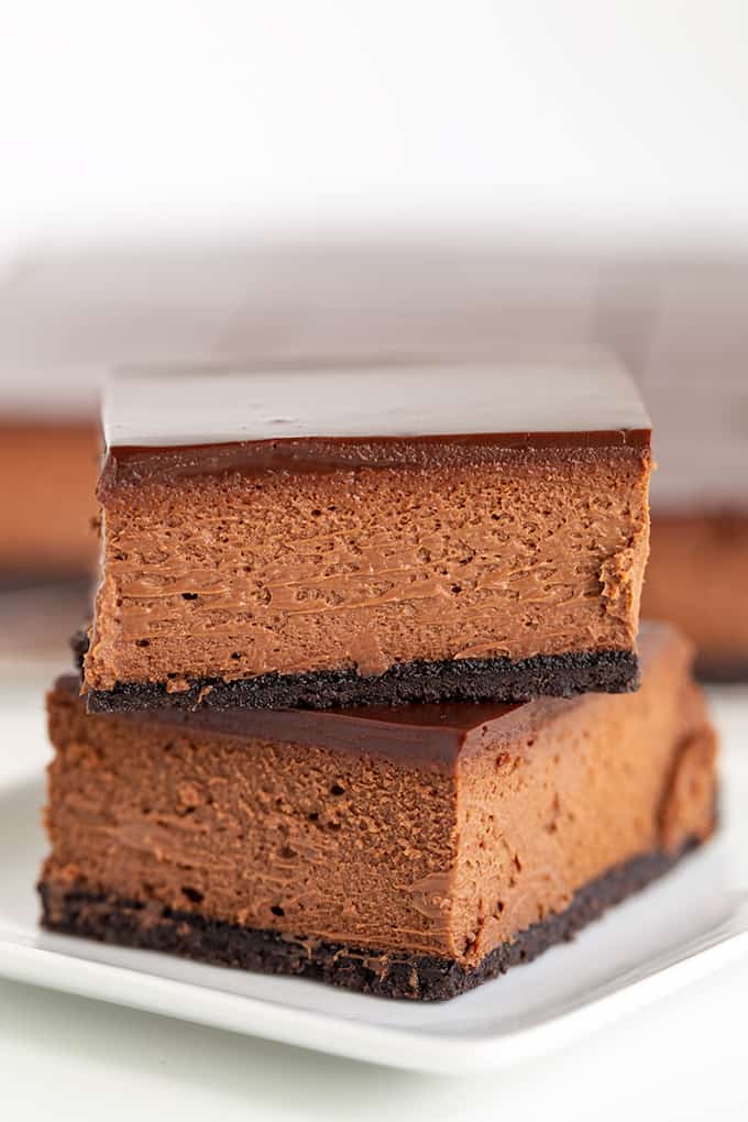 A stack of chocolate cheesecake bars on a white plate.