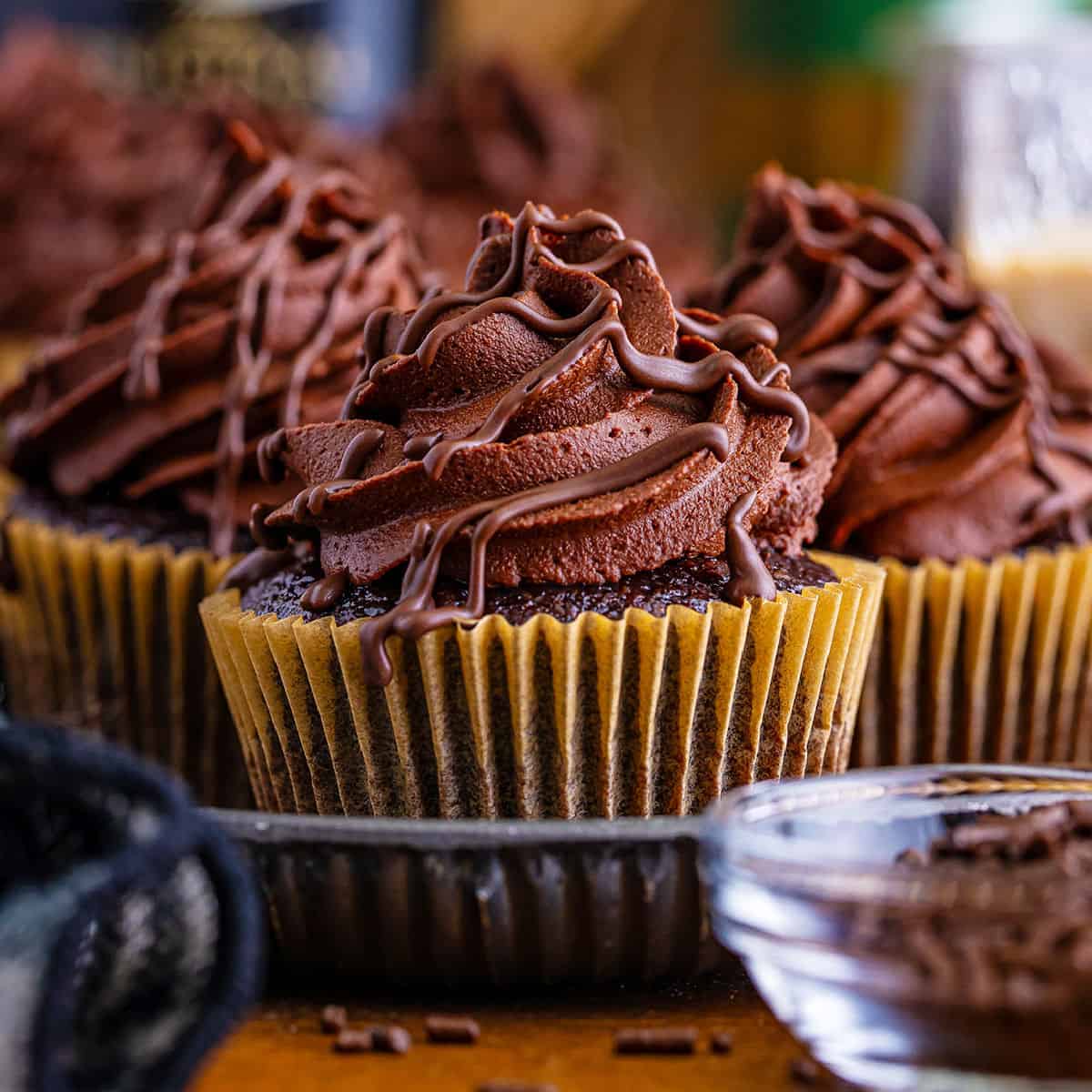 Chocolate cupcakes with Baileys frosting and shavings displayed on a wooden surface.