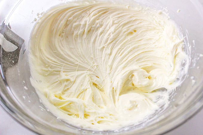 A glass bowl filled with smooth, freshly whipped lemon delight cream cheese frosting.
