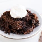 A plate of chocolate lava cake topped with a dollop of whipped cream sits next to a slice of decadent Oreo Dump Cake.