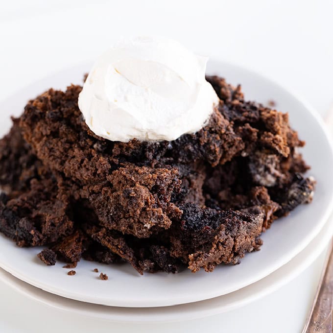 A plate of chocolate lava cake topped with a dollop of whipped cream sits next to a slice of decadent Oreo Dump Cake.