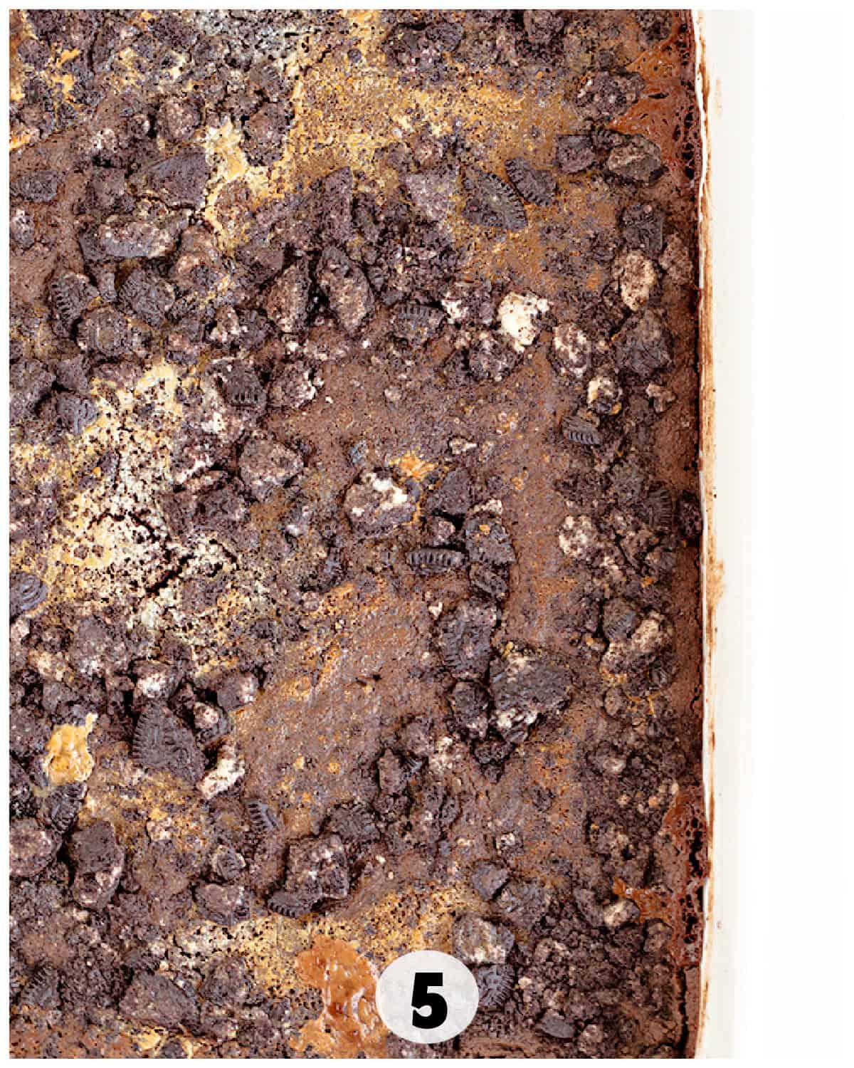 A top view of an Oreo Dump Cake topped with crumbled cookies and a labeled number "5" in a white circle at the bottom edge.