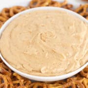 A white bowl filled with a creamy dip is placed in the center of a plate surrounded by pretzels, resembling the comfort of a classic cream pie.