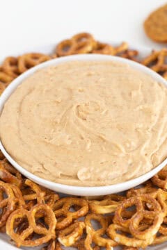 A white bowl filled with a creamy dip is placed in the center of a plate surrounded by pretzels, resembling the comfort of a classic cream pie.