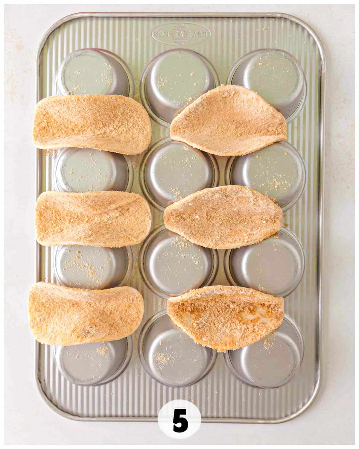 Upside-down muffin tray with four taco shells placed between the cups, in the process of being baked, reminiscent of a creative apple pie twist.