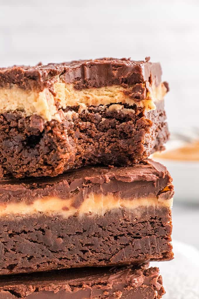A stack of buckeye brownies, featuring a creamy layered filling, is elegantly set against a neutral background.