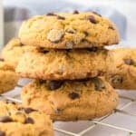 Four cream cheese chocolate chip cookies stacked on a cooling rack.