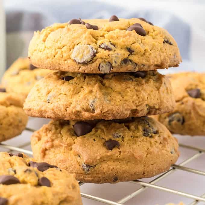 Four cream cheese chocolate chip cookies stacked on a cooling rack.