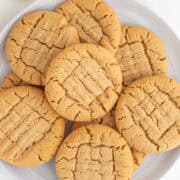 A plate of chewy, crisscross-patterned peanut butter cookies sits invitingly next to a refreshing glass of milk.