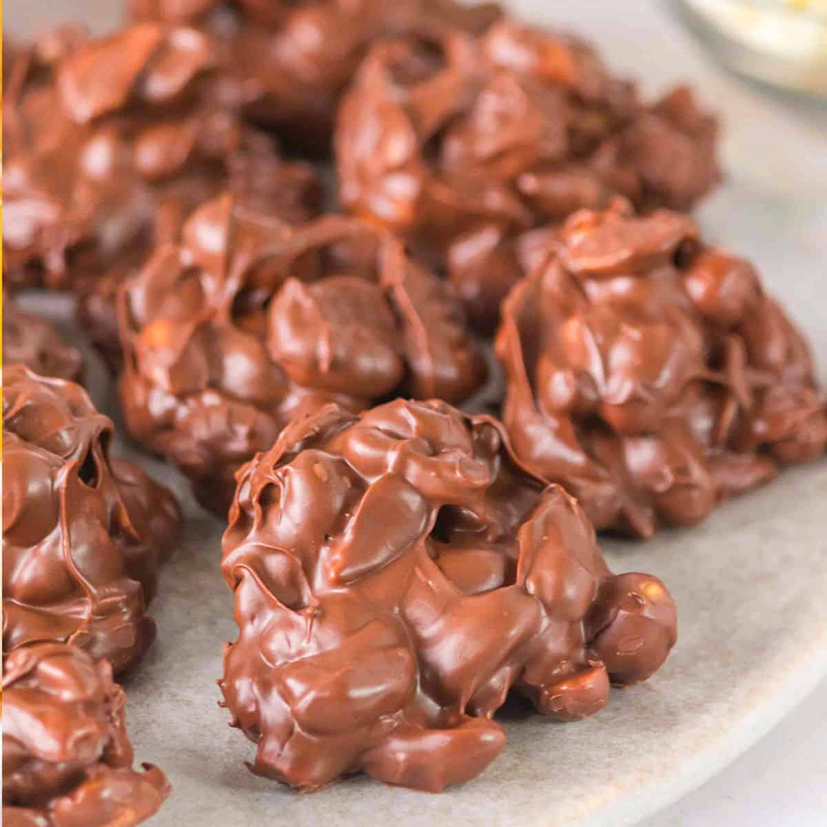 Close-up of Crockpot Candy chocolate nut clusters elegantly arranged on a plate.