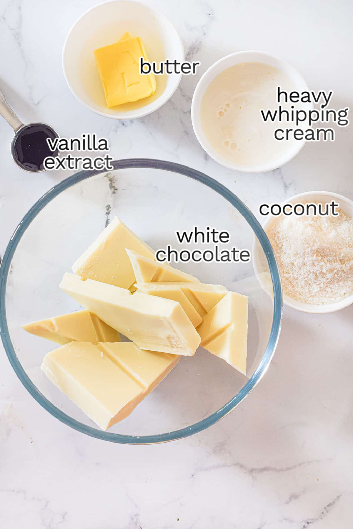 A delightful assembly for a coconut-infused treat: a bowl with white chocolate pieces, butter, heavy whipping cream, vanilla extract, and shredded coconut await transformation into luscious truffles on the marble surface.