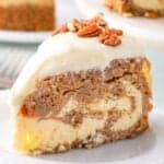 A slice of cake with cream cheese frosting and pecans on top, featuring layers of chocolate, vanilla, and a hint of carrot cake magic, served on a white plate.