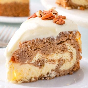 A slice of cake with cream cheese frosting and pecans on top, featuring layers of chocolate, vanilla, and a hint of carrot cake magic, served on a white plate.