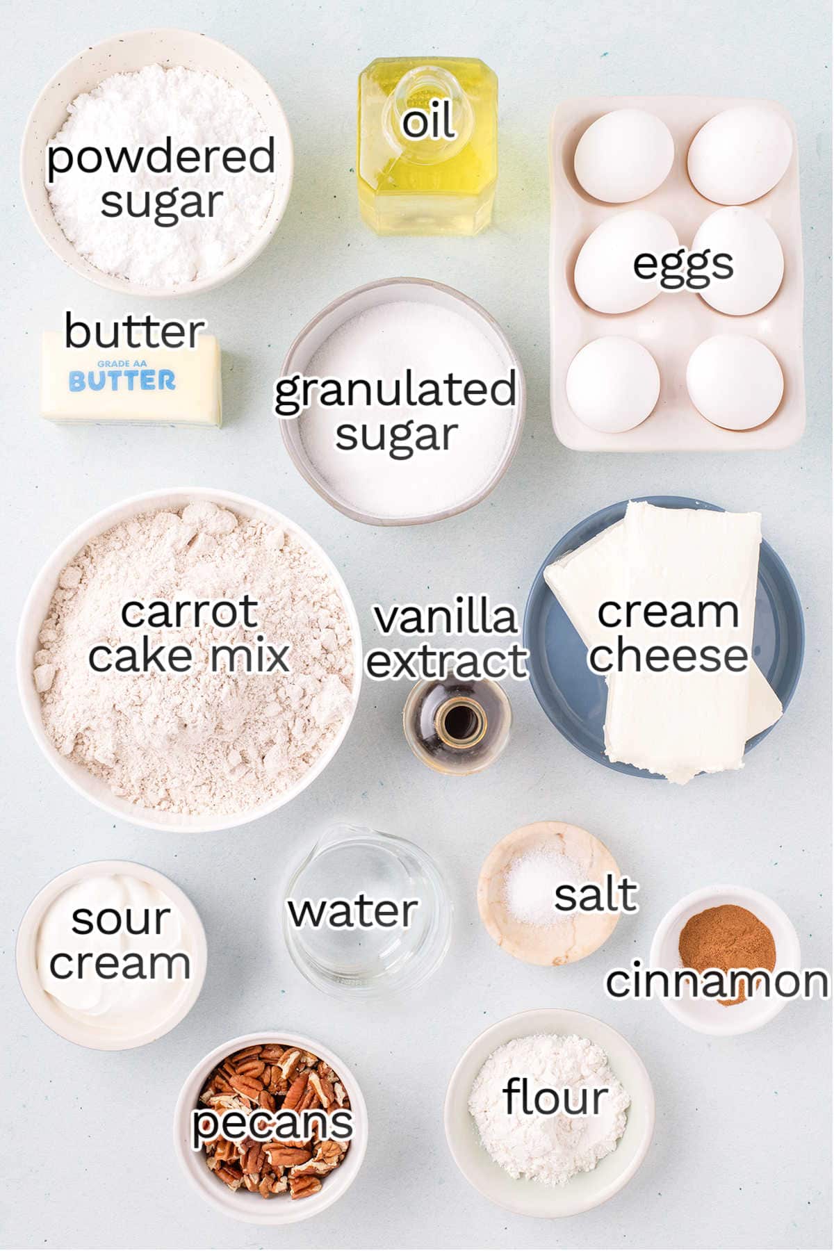 Ingredients for a delectable carrot cheesecake include powdered sugar, butter, oil, eggs, granulated sugar, carrot cake mix, vanilla extract, cream cheese, sour cream, water, salt, cinnamon, pecans and flour.