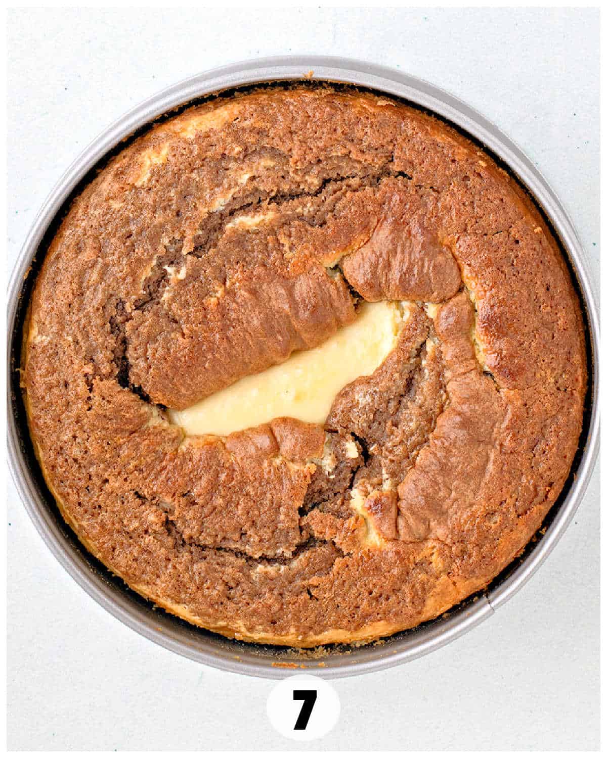 A round marble cake in a baking pan, marked with a "7," sits beside a tantalizing slice of carrot cake cheesecake.
