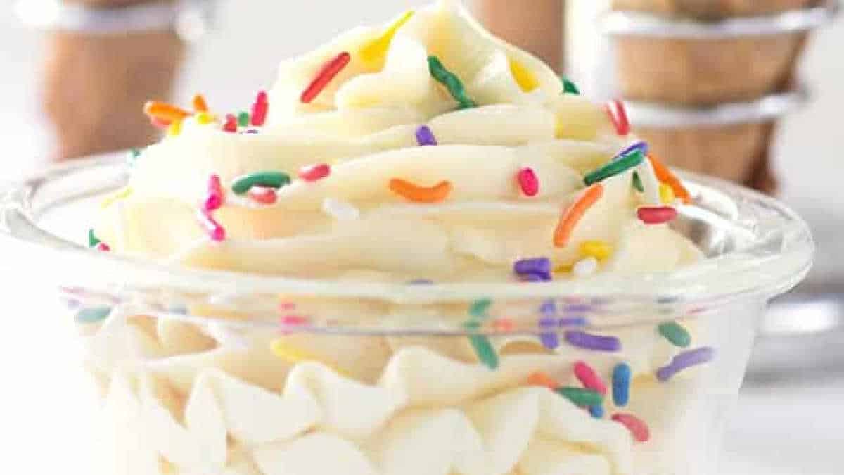 A glass dessert cup filled with whipped cream and topped with colorful rainbow sprinkles is a delightful treat. Perfect for those seeking creative cake mix recipes.