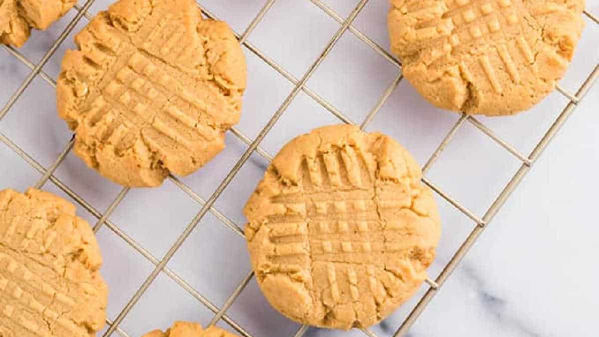 Peanut butter cookies with signature fork marks, resting on a cooling rack over a marble surface—these delightful treats make perfect additions to your collection of cake mix recipes.