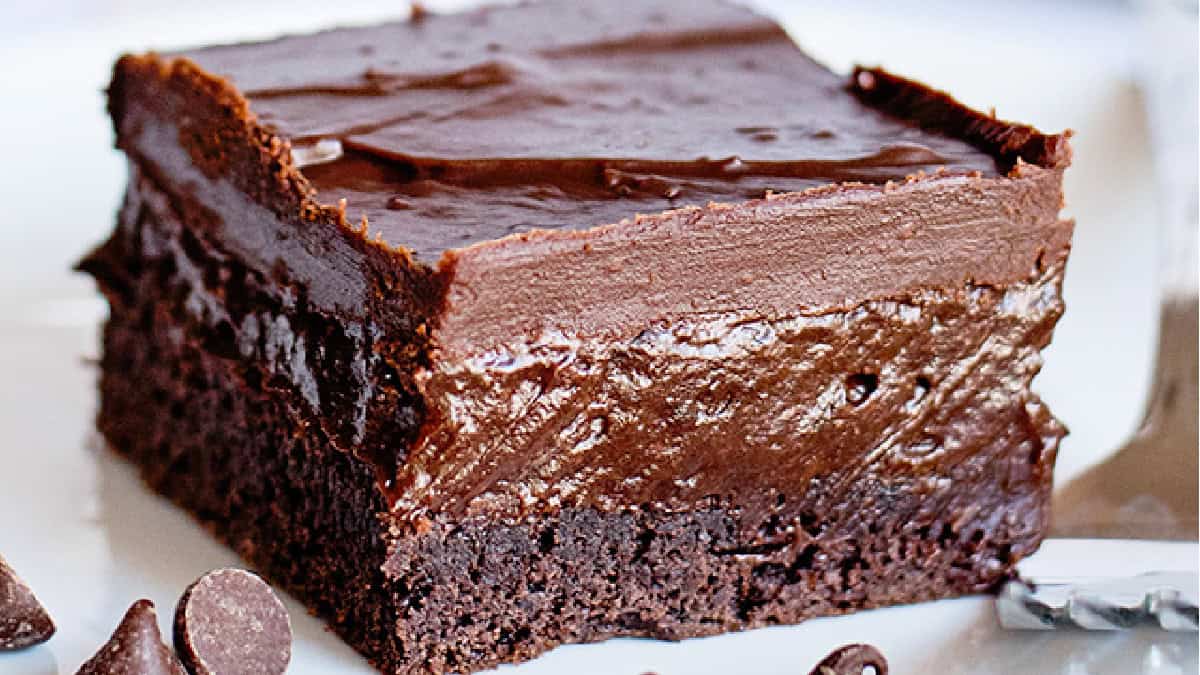 A close-up of a chocolate brownie crafted from a cake mix, topped with a thick, glossy layer of chocolate ganache.