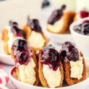 blueberry cheesecake tacos on a small white rimmed plate with blueberries scattered around and a red and white striped linen next to the plate