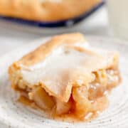 A slice of Apple Slab Pie with a golden crust and visible apple filling sits on a white speckled plate.