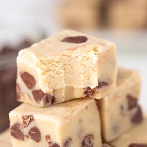 Close-up of a stack of Cookie Dough Fudge squares, with the top piece showing a bite taken out.