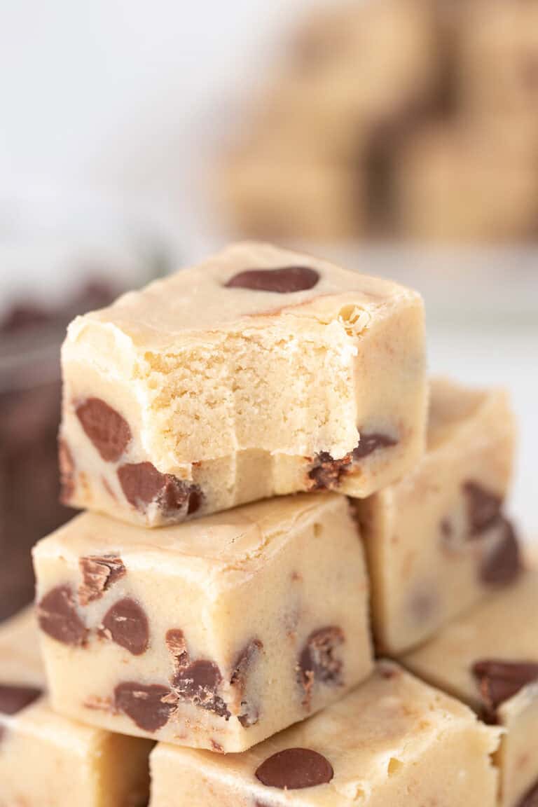Close-up of a stack of Cookie Dough Fudge squares, with the top piece showing a bite taken out.