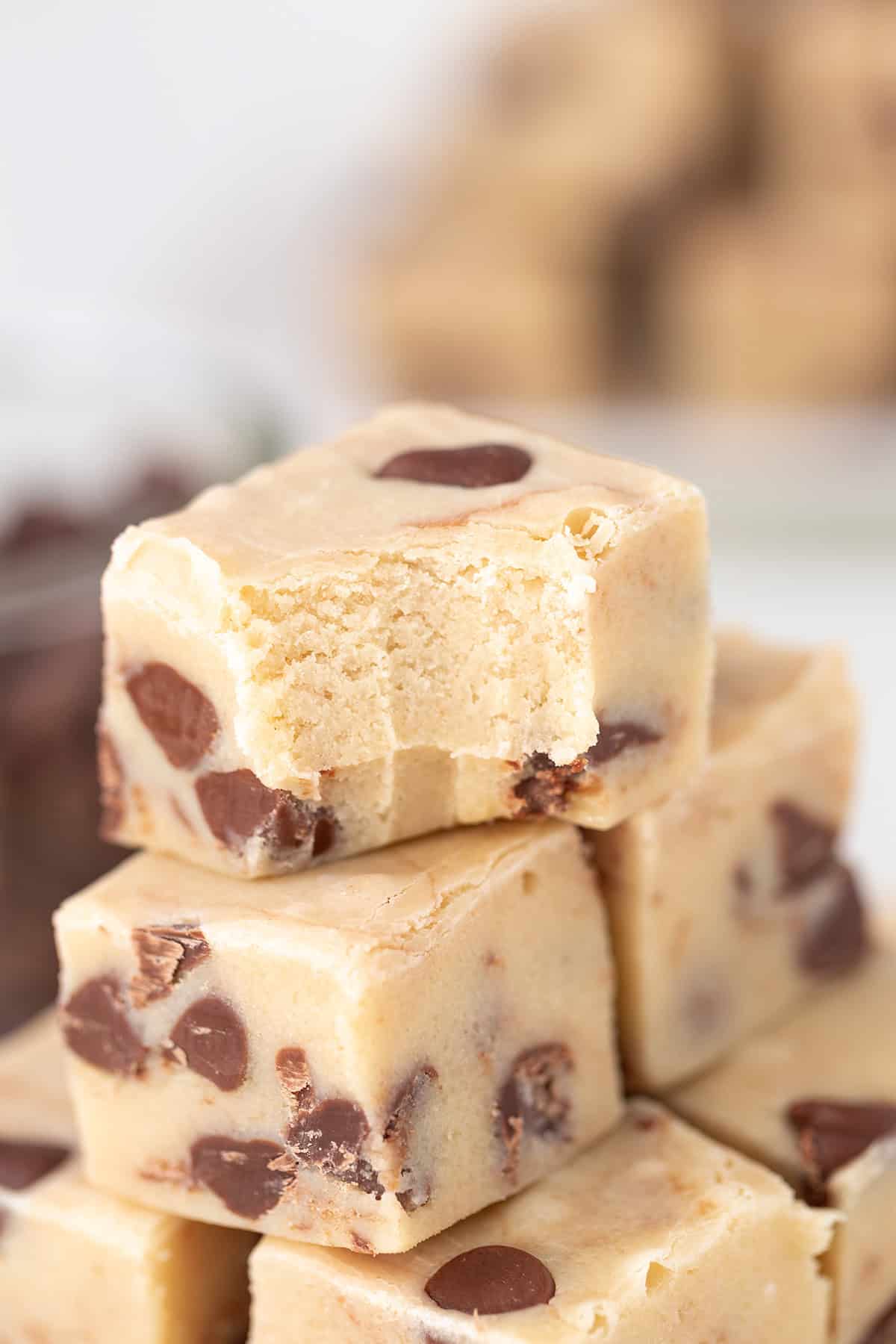 Close-up of a stack of Cookie Dough Fudge squares, with the top piece showing a bite taken out.