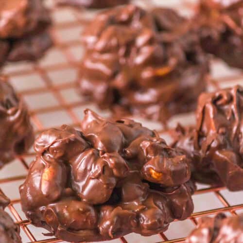 Clusters of chocolate-covered nuts, reminiscent of classic Turtle Candy, are cooling on a wire rack after being melted together in the Crockpot.