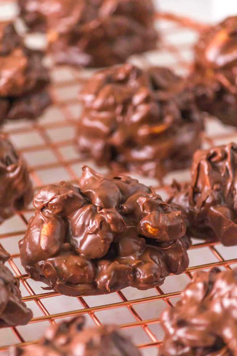 Clusters of chocolate-covered nuts, reminiscent of classic Turtle Candy, are cooling on a wire rack after being melted together in the Crockpot.