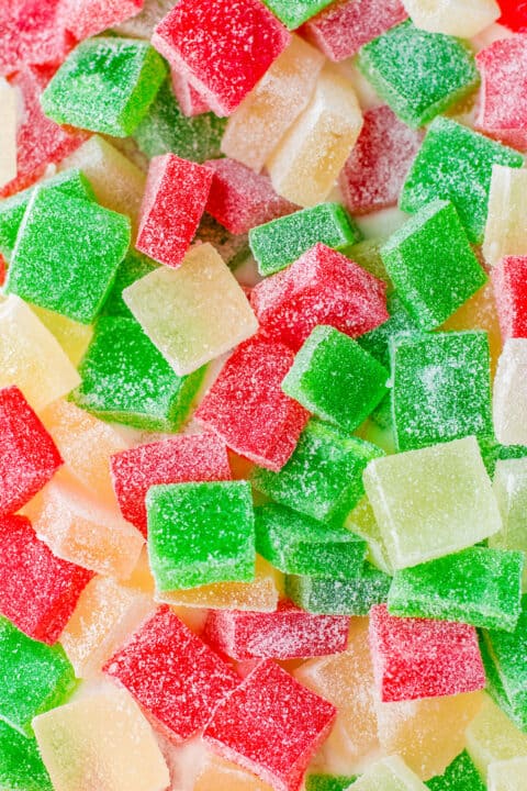 Brightly colored red, green, and yellow sugar-coated homemade gumdrops are scattered in a close-up view, perfect as festive Christmas candy.