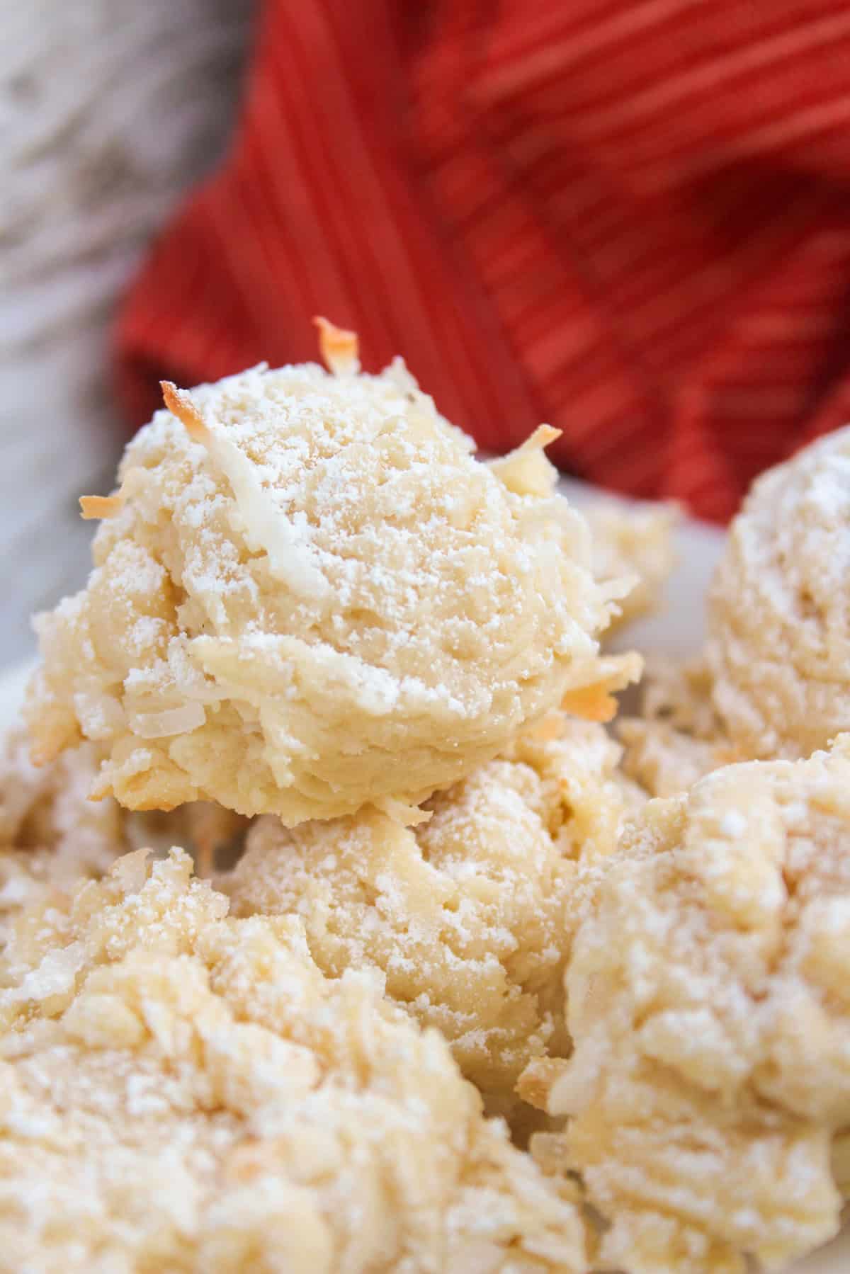Close-up of coconut macaroons made with sweetened condensed milk and dusted with powdered sugar, with a red cloth in the background.