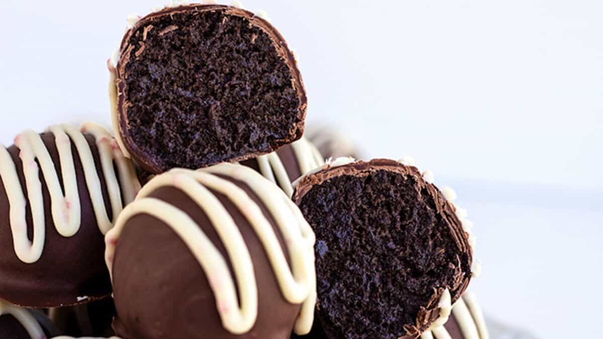 A close-up of chocolate cake balls with a dark cake center, coated in chocolate and drizzled with white chocolate—perfect for St. Patrick's Day or as a festive mint chocolate dessert.