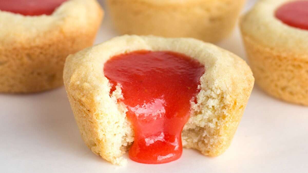 A close-up of a cookie cup filled with red jelly, with jelly oozing out from a bite taken in the front—perfect for fans of spring desserts and creative lemon recipes.
