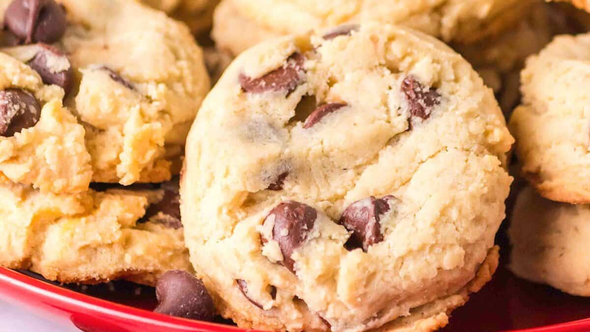 A close-up of several chocolate chip cookies with a soft, chunky texture&mdash;classic pantry staples&mdash;arranged on a red plate.