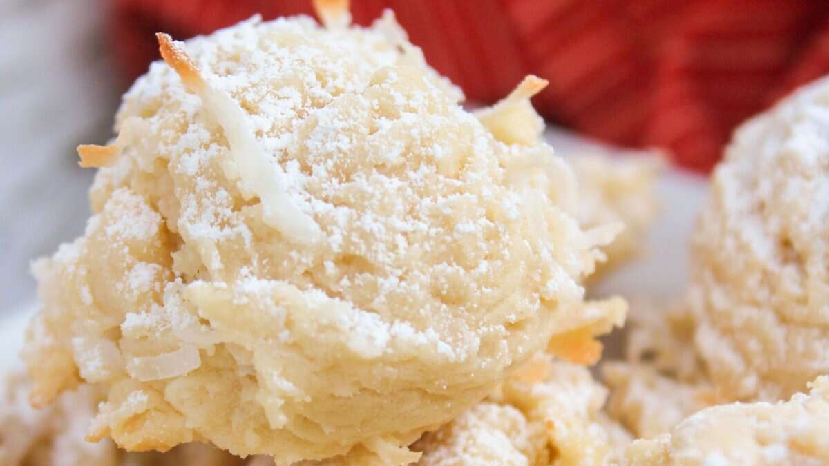 A close-up of coconut macaroons dusted with powdered sugar, with a red cloth in the background&mdash;one of those easy cookie recipes you can make with pantry staples.