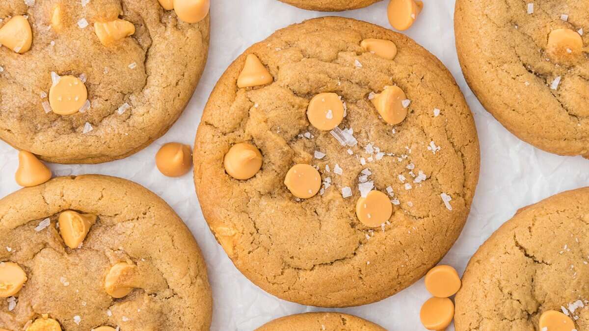 Close-up of several round cookies with butterscotch chips and a sprinkling of coarse salt on parchment paper&mdash;perfect for those seeking easy cookie recipes using pantry staples.