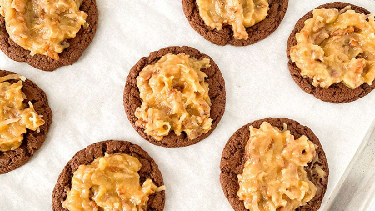 Eight chocolate cookies topped with a caramel and nut mixture are arranged on white parchment paper&mdash;perfect for anyone seeking easy cookie recipes made with pantry staples.