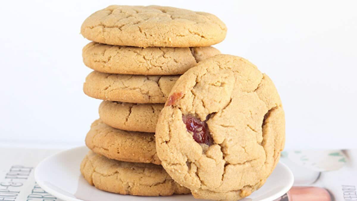 A stack of six golden-brown cookies sits on a white plate, with one cookie leaning against the stack&mdash;a perfect treat made from simple pantry staples and easy cookie recipes.